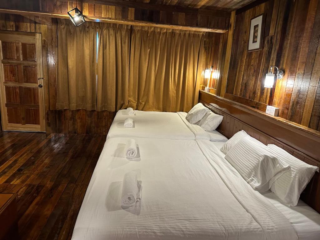 Joe Fisherman Inn في بانكور: زوج من الأسرة في غرفة نوم ذات جدران خشبية