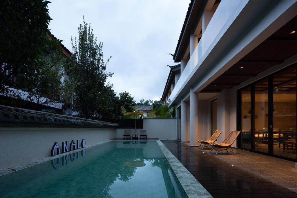 a swimming pool with two chairs next to a building at ANALO Resort Hotel in Lijiang