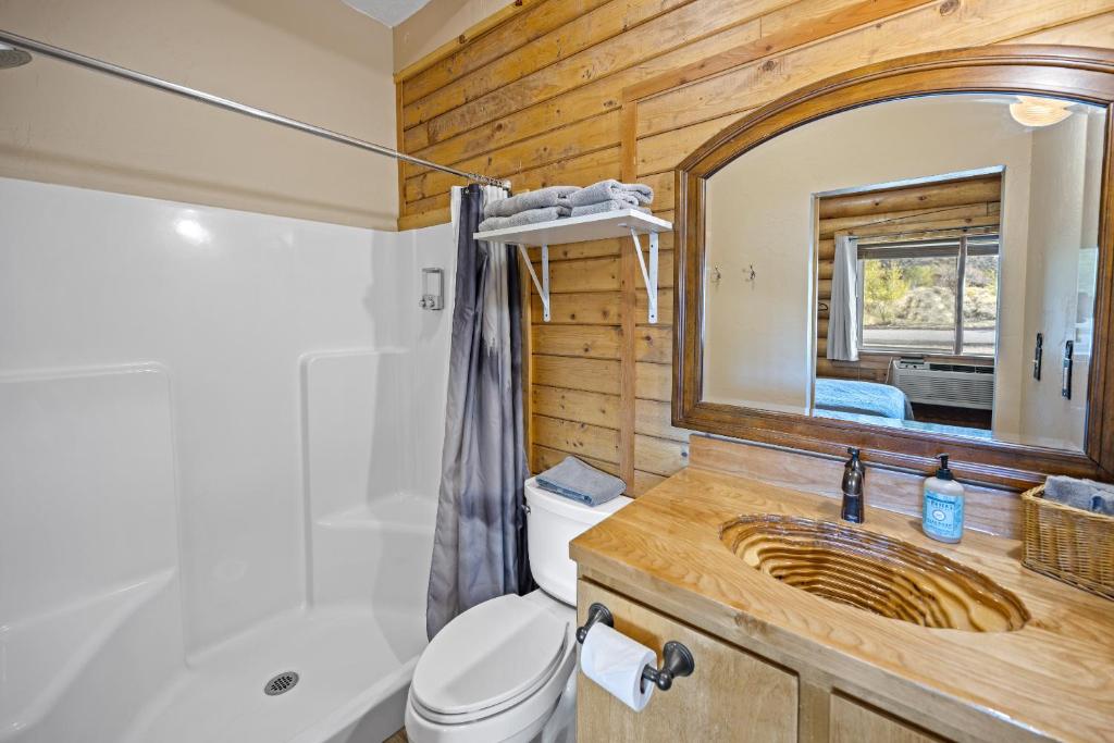 Un baño con inodoro, lavabo y espejo. en Ponderosa Inn, en Escalante