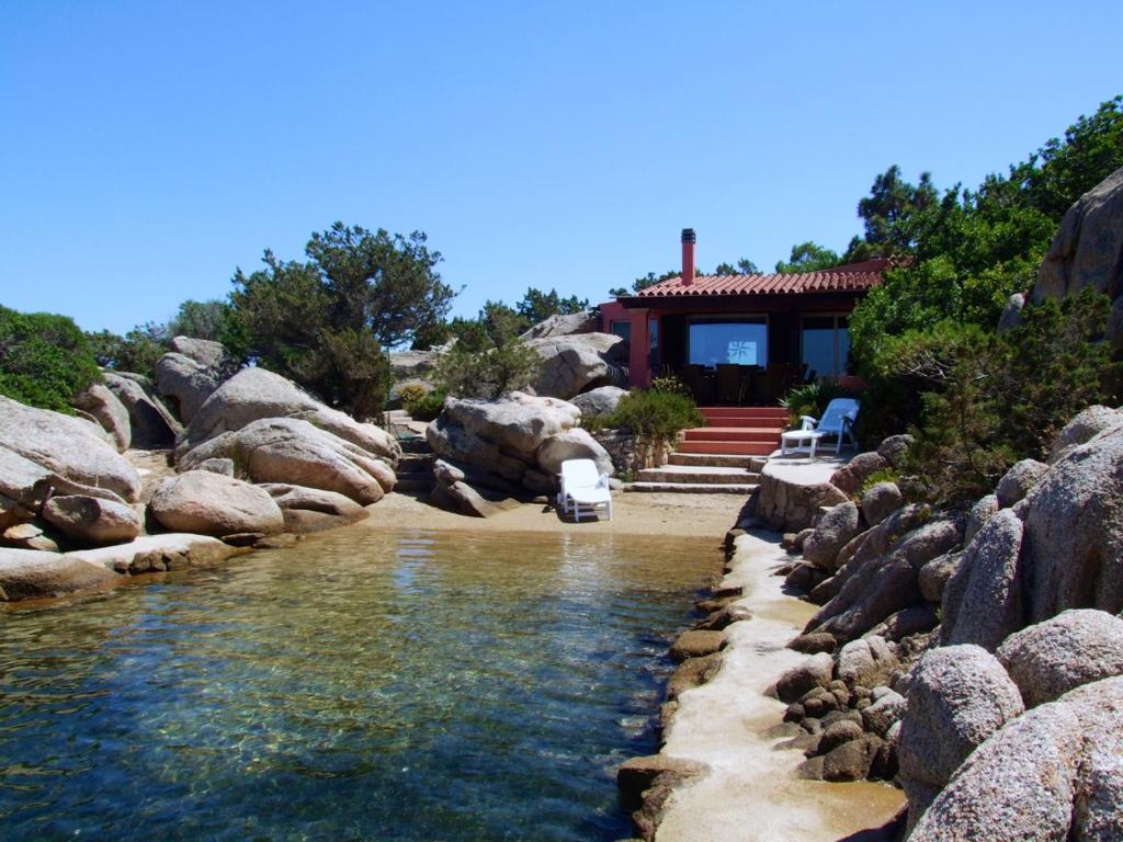 a house sitting next to a river with rocks at Villa Mica in La Maddalena