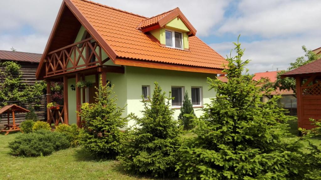 una casa con techo naranja y algunos árboles en Zielony Domek Kruklanki, en Kruklanki