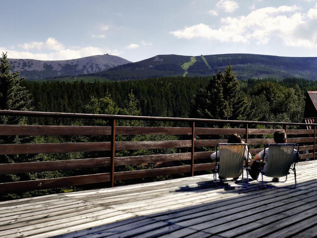 Dos personas sentadas en sillas en una terraza con vistas a las montañas en Dom Wczasowo Rekreacyjny Zgoda, en Karpacz