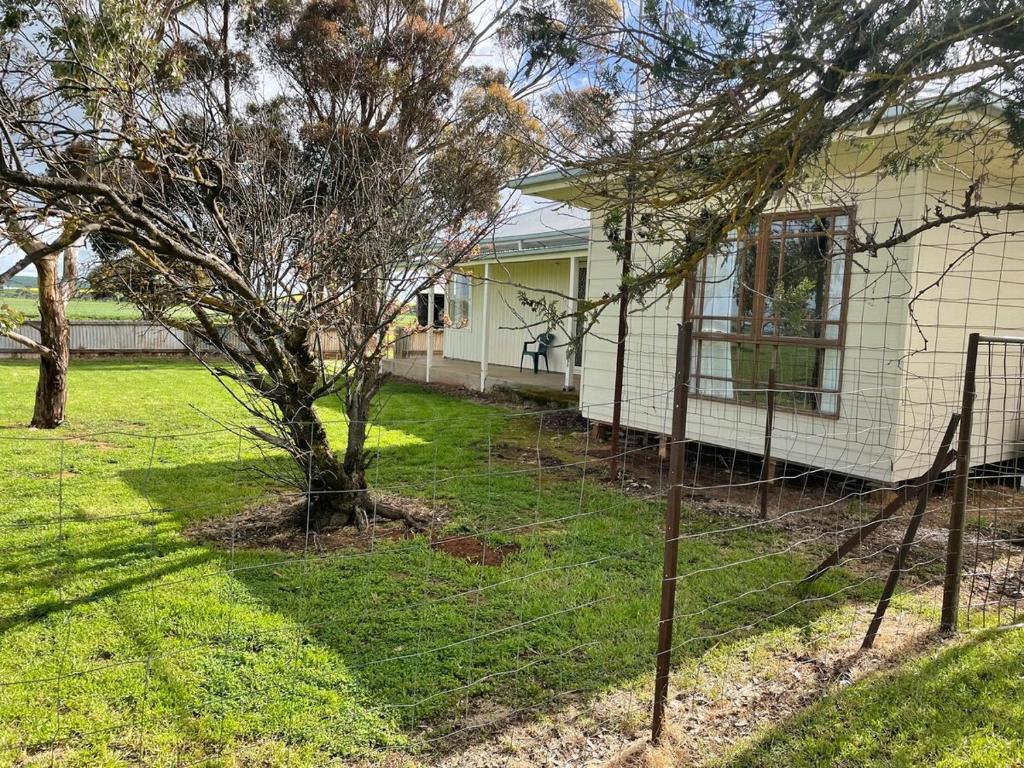a fence in front of a house with a tree at The Vale Farmhouse Rural Setting in Farrell Flat