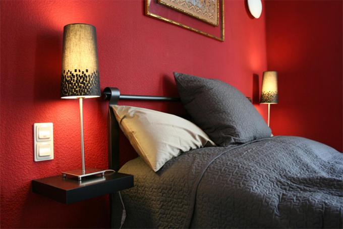 a bedroom with a red wall with a bed and two lamps at Strumpfeck Suites in Traben-Trarbach