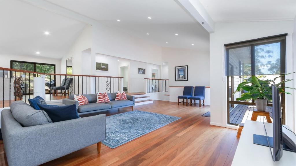 a living room with a couch and a table at 'Treetops On The Bay - Water Views' by HolidayCo in Hardys Bay