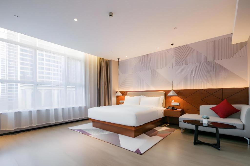 ein Schlafzimmer mit einem weißen Bett, einem Sofa und einem Fenster in der Unterkunft Borrman Hotel Xi'an North High-speed Railway Station in Xi'an