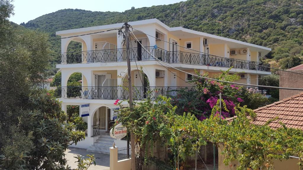 ein großes weißes Gebäude mit Balkonen und Bäumen in der Unterkunft Captain Georgio Apartments in Póros