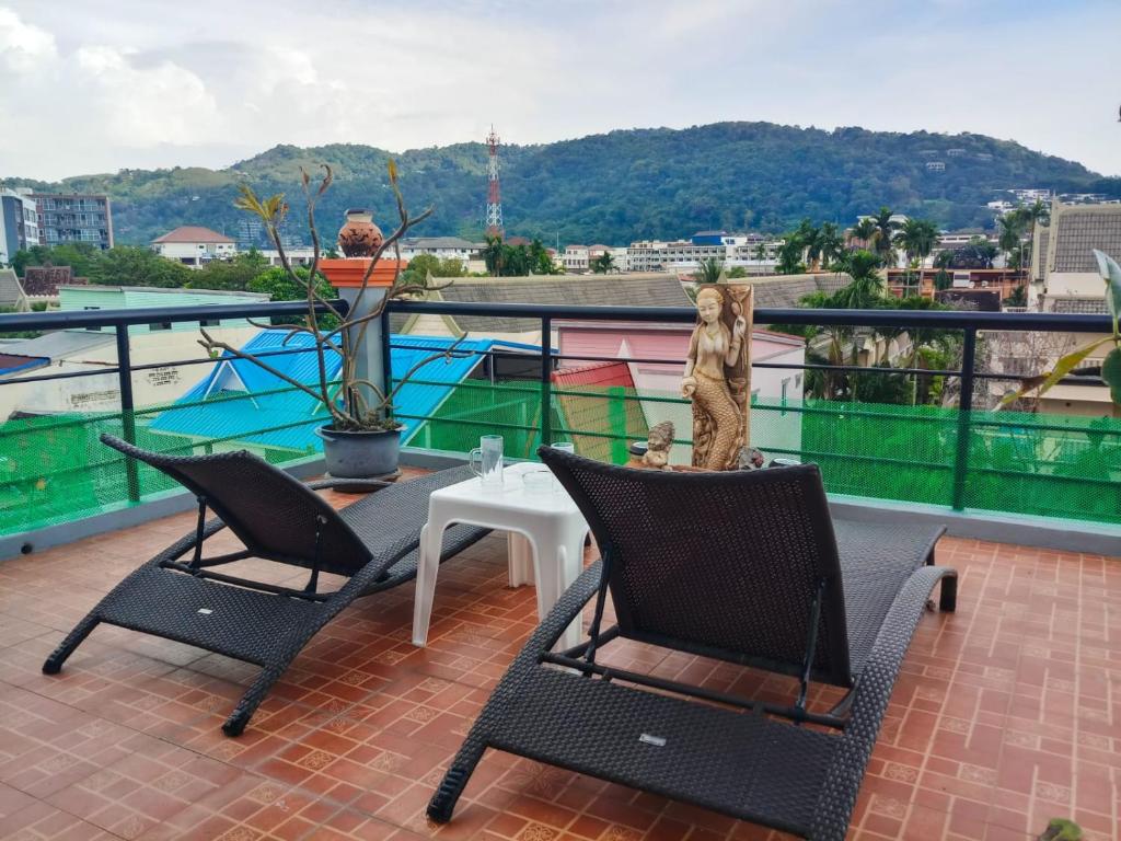 een terras met twee stoelen en een tafel op een balkon bij Kata Lina rooftop in Kata Beach