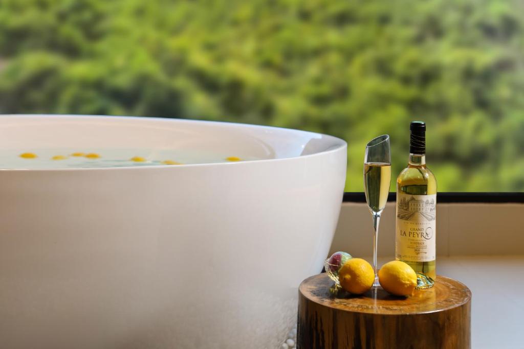 eine Flasche Champagner und ein Glas neben einer Wanne in der Unterkunft Xingyun Mujing Hotel in Yangshuo