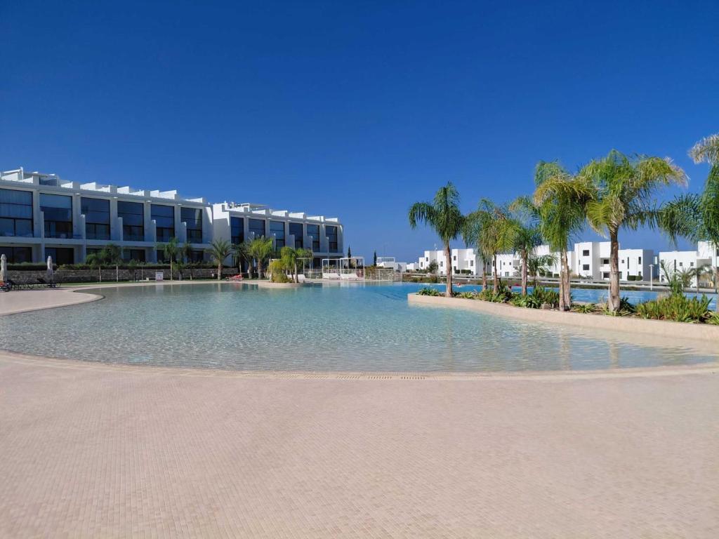 a large swimming pool with palm trees and a building at Apartment Maldives in Khóti Nisí
