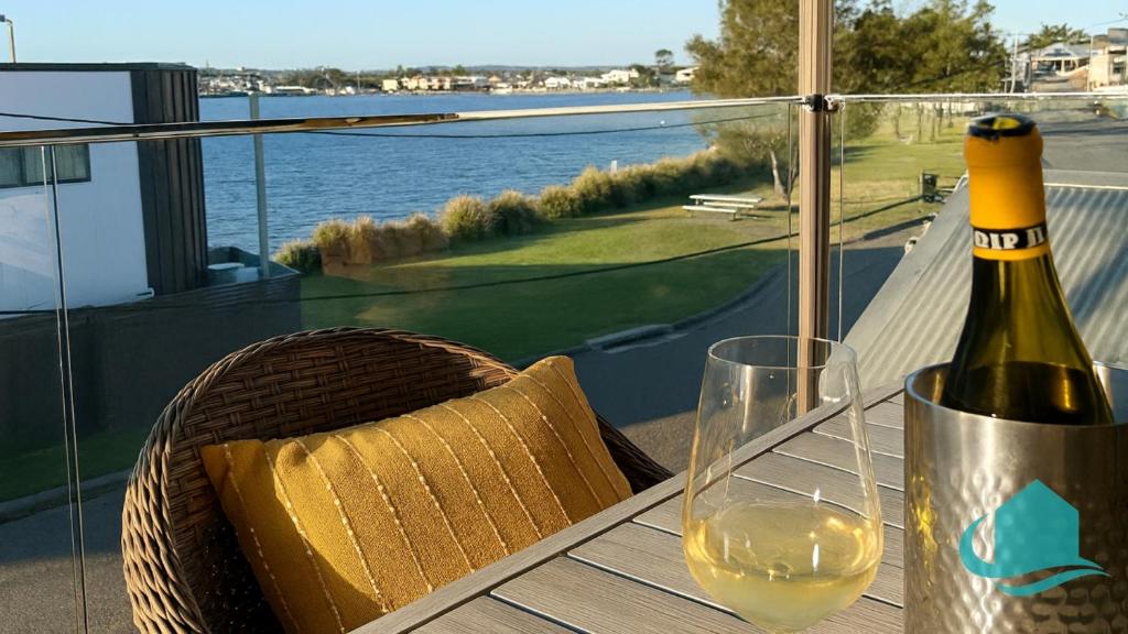a bottle of wine sitting on a table with a glass at Village Bay Lake house family Lake House with Spa in Marks Point