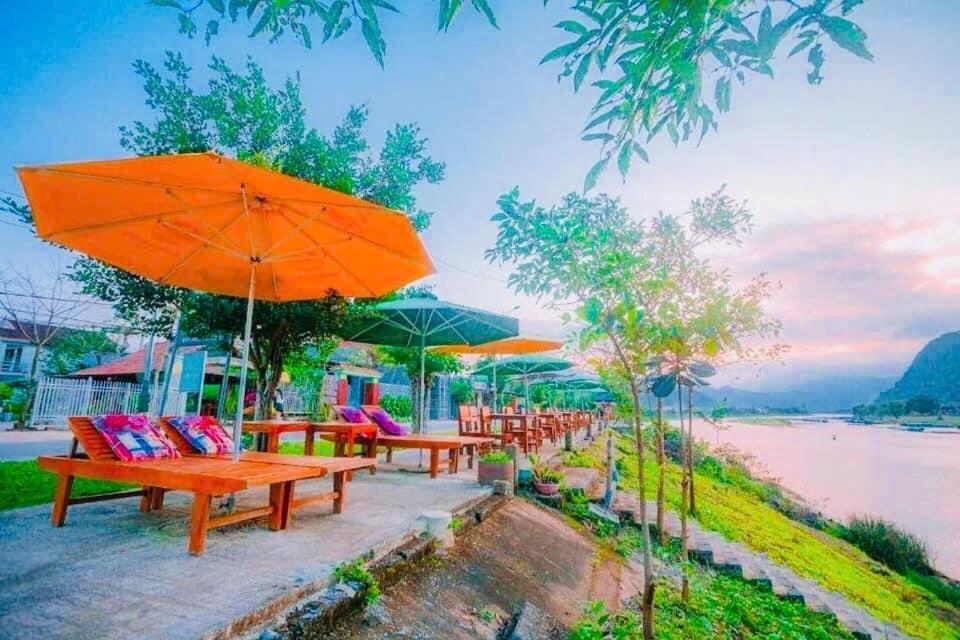 una fila di panchine con ombrelloni su una spiaggia di Phong Nha Garden House a Phong Nha