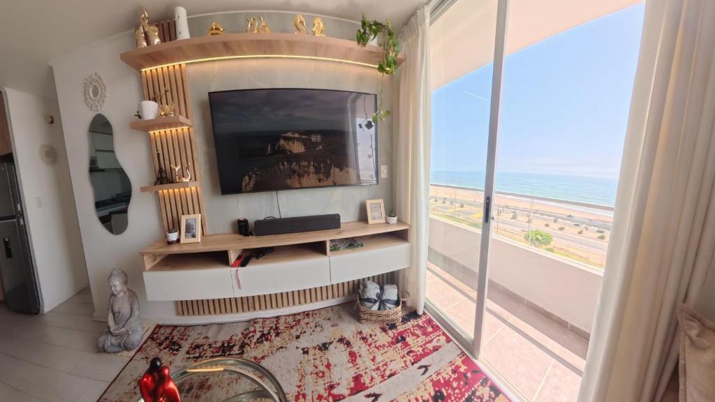 a living room with a television and a view of the beach at Ocean Blue, Vista Frontal Al Mar in Lima
