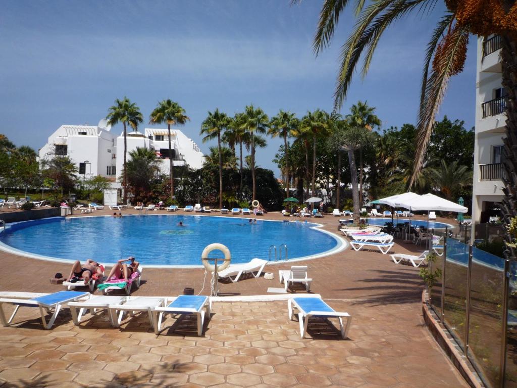 una piscina con personas sentadas en tumbonas en un complejo en Estudio Edificio El Dorado, en Playa de las Américas