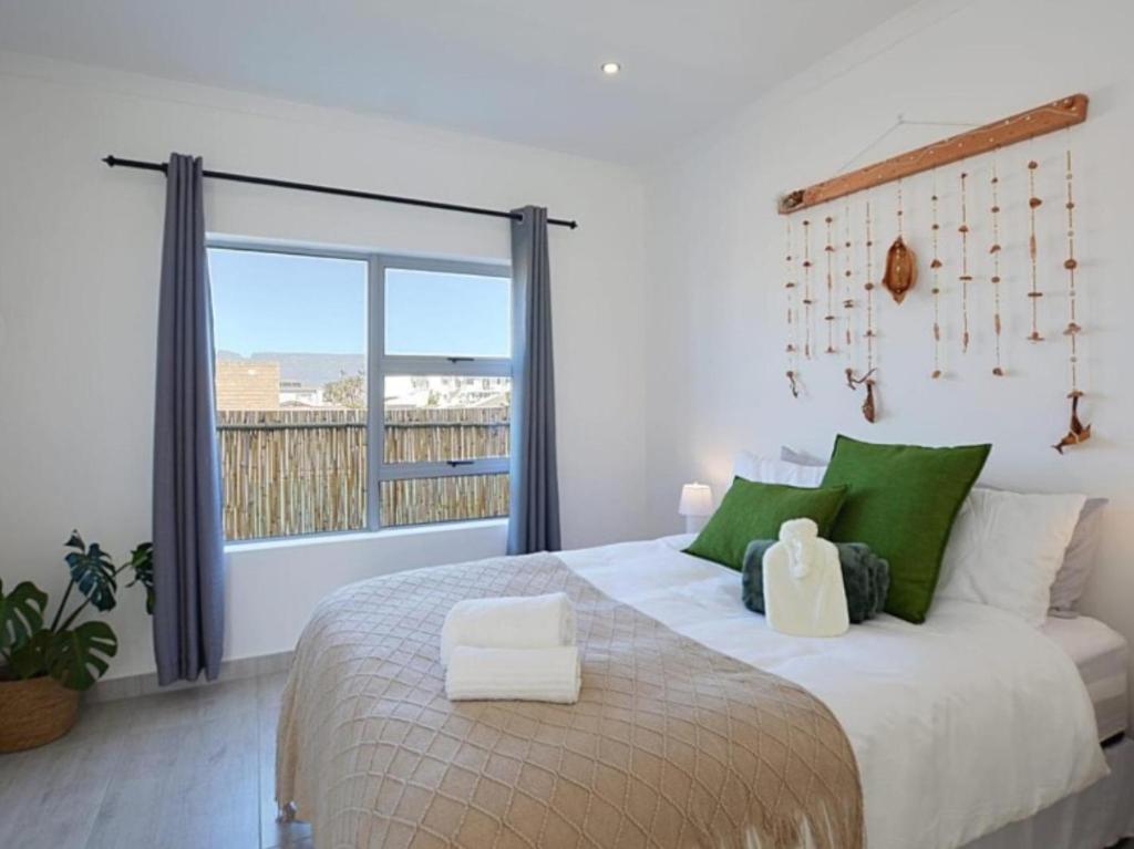 a bedroom with a bed with green pillows and a window at Blouberg, Nautica and Studio Apartments in Cape Town