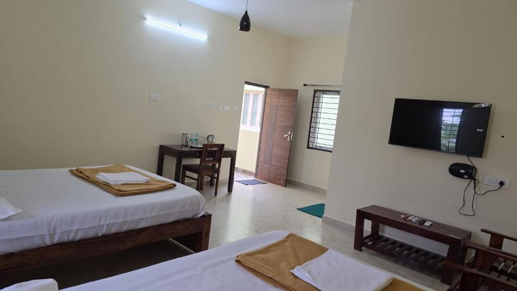 a room with two beds and a television on the wall at ShivOhome in Tiruvannāmalai