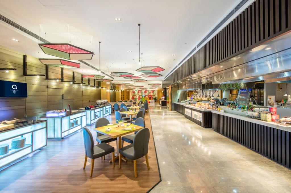 The QUBE Hotel Jingzhou في Caoshi: مطعم به طاولات وكراسي وكافتيريا