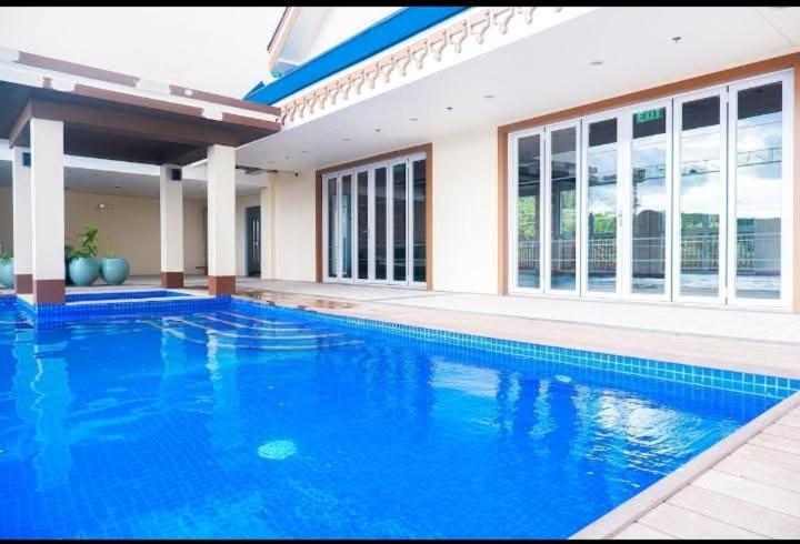 ein großer blauer Swimmingpool vor einem Haus in der Unterkunft Twinlakes Tagaytay Vinesera Manor1 3F in Balibaguhan