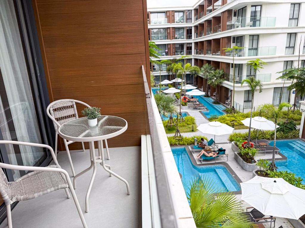 a balcony with a table and chairs and a swimming pool at Sunshine Layan Beach Resort studio #84191 in Layan Beach