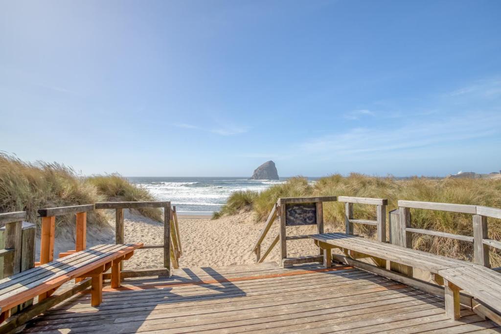 a wooden walkway to the beach with two benches at BeachLovers Getaway in Pacific City