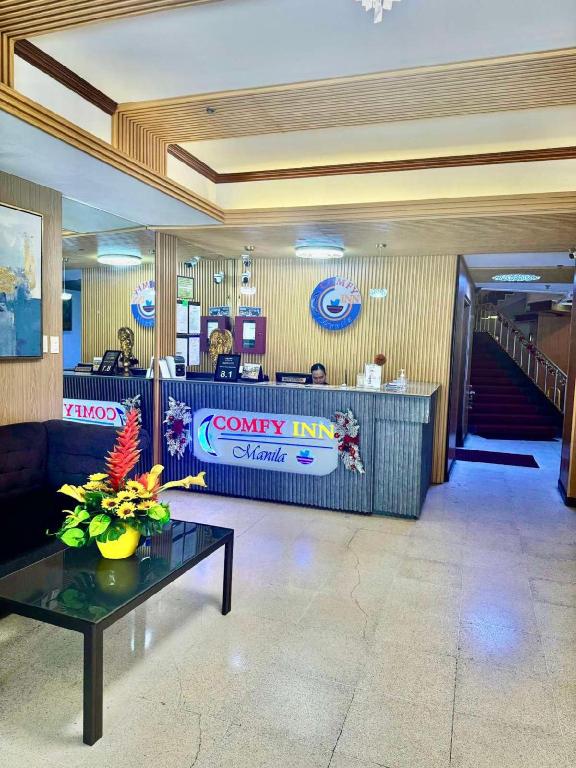 a lobby with a waiting area with a counter and a table at Comfy Inn Mabini Manila in Manila
