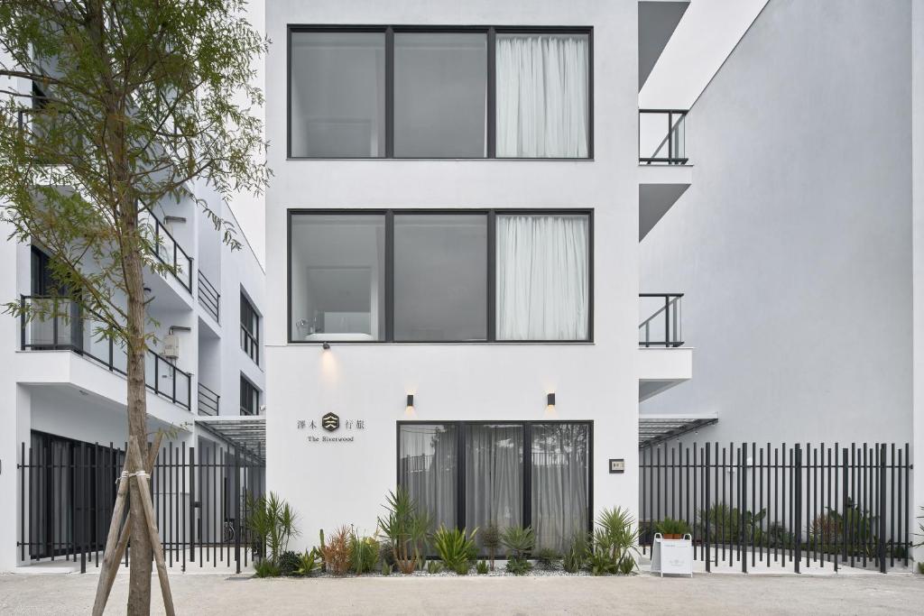 una fachada de un edificio blanco con ventanas negras en 澤木行旅 The Riverwood, en Yilan City