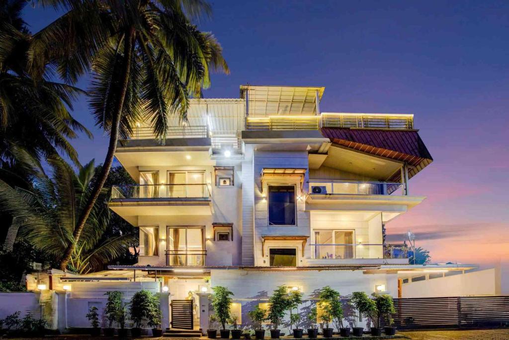 una grande casa bianca con palme di fronte di Casa Swarg a Parra