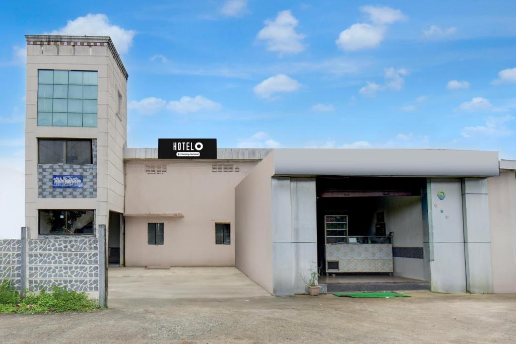 浦那Hotel O Talegaon MIDC Formerly Goodluck Lodge的一座白色建筑，顶部有一块招牌