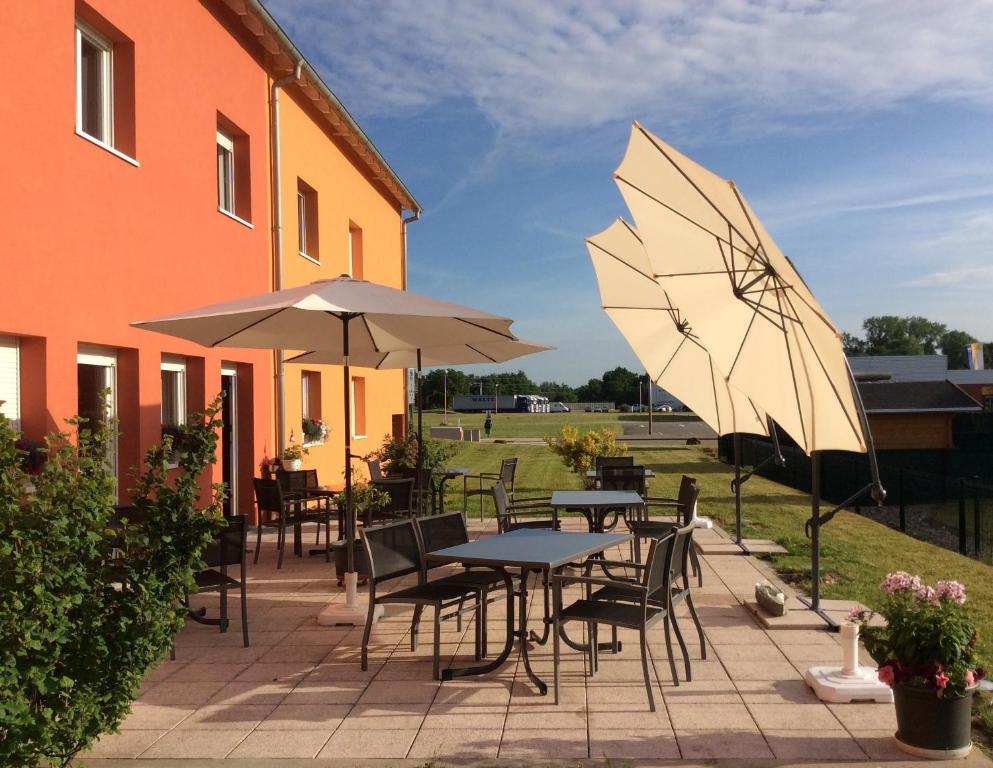 a patio with tables and umbrellas next to a building at Hôtel Des Bois in Seltz