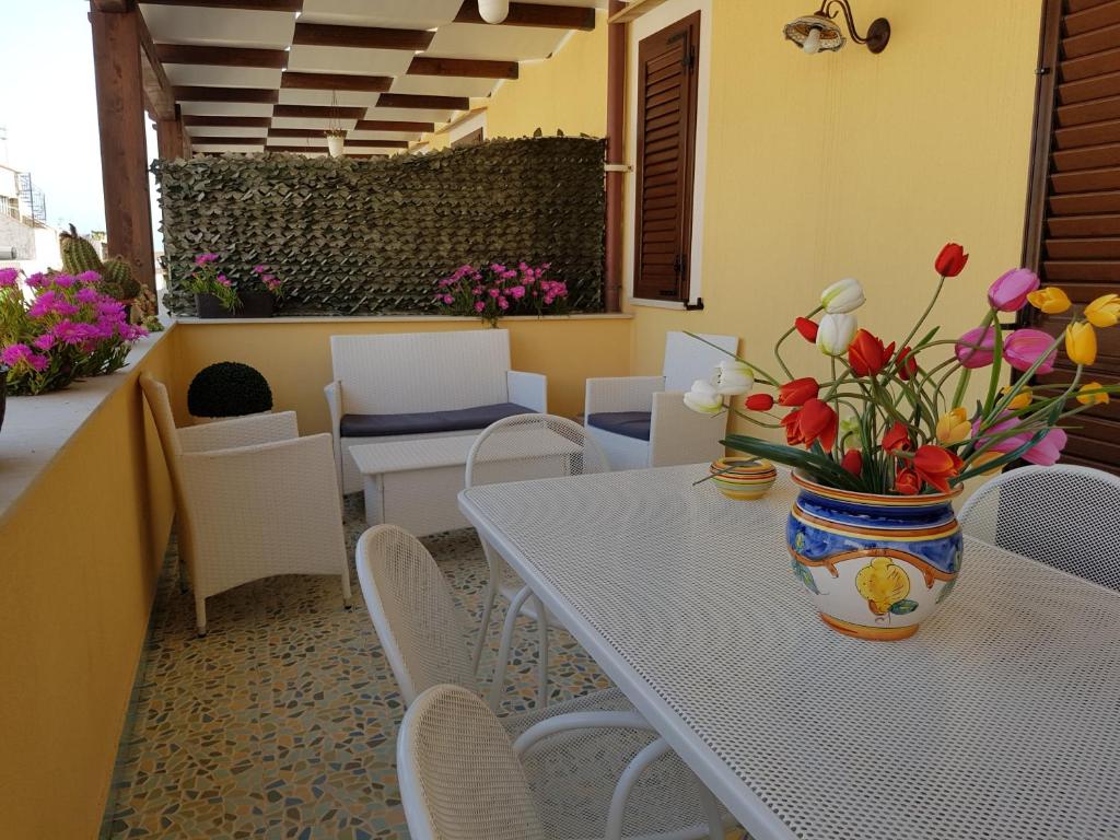 ein Tisch und Stühle mit einer Blumenvase drauf in der Unterkunft Aurora Apartments and Spa in San Vito lo Capo