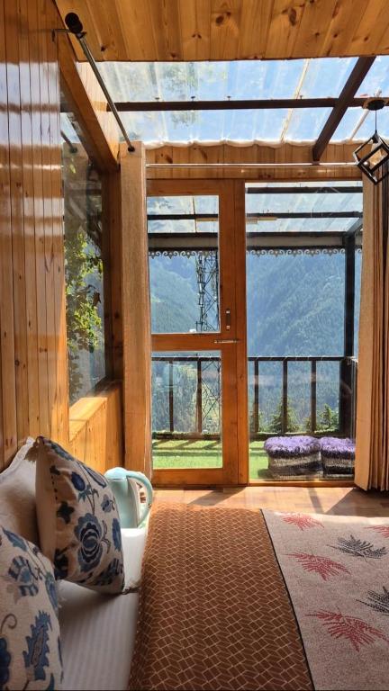 a bedroom with a bed and a large window at Skyview Jacuzzi Treehouse Power Backup Tandi in Kulu