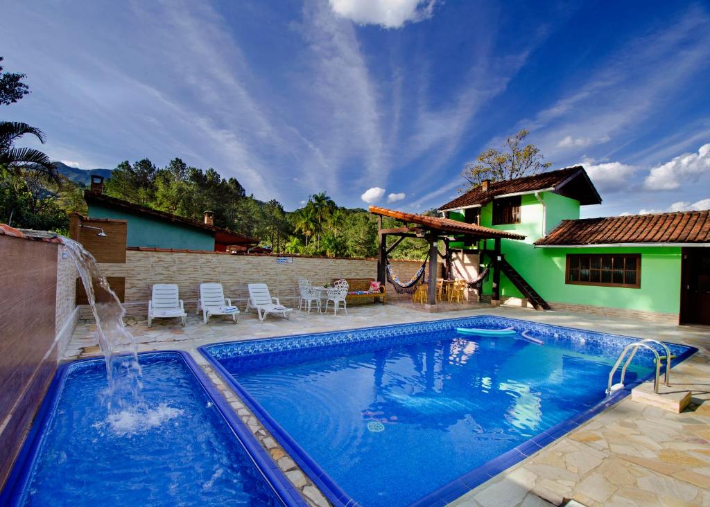 a swimming pool with a fountain in front of a house at Pousada Sabor da Serra in Visconde De Maua