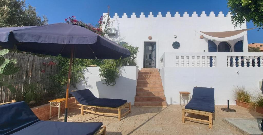 a patio with two chairs and an umbrella at Riad Diaz Taghazout in Taghazout