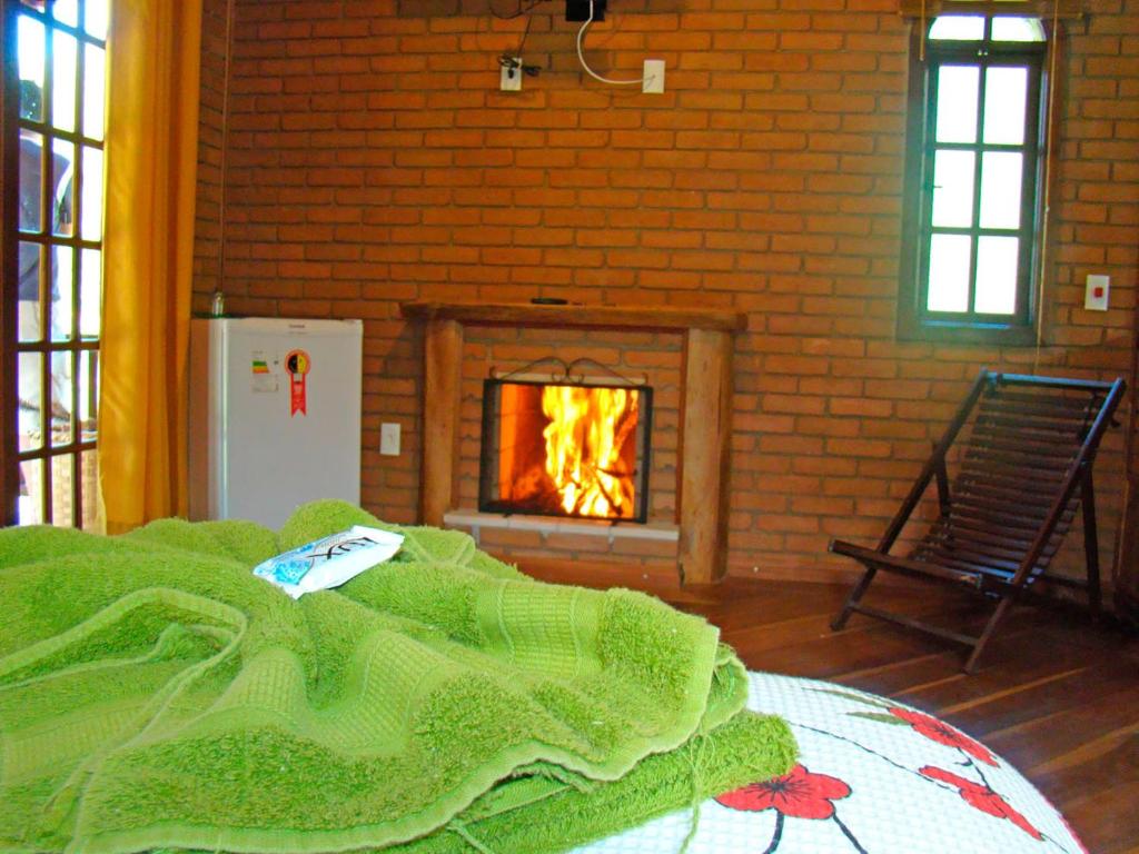 una camera da letto con camino e un letto con una coperta verde di Pousada Solar Das Águas, S/N a Visconde De Maua