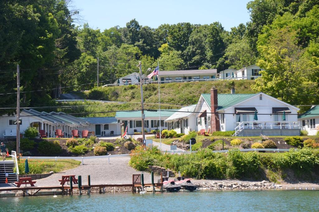 a small boat in the water next to a house at Lake View Motel in Cooperstown