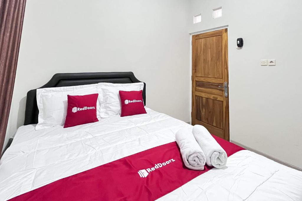 a bedroom with a bed with red and white pillows at RedDoorz Syariah Omah Audrey near RSI Kota Magelang in Kedungsari