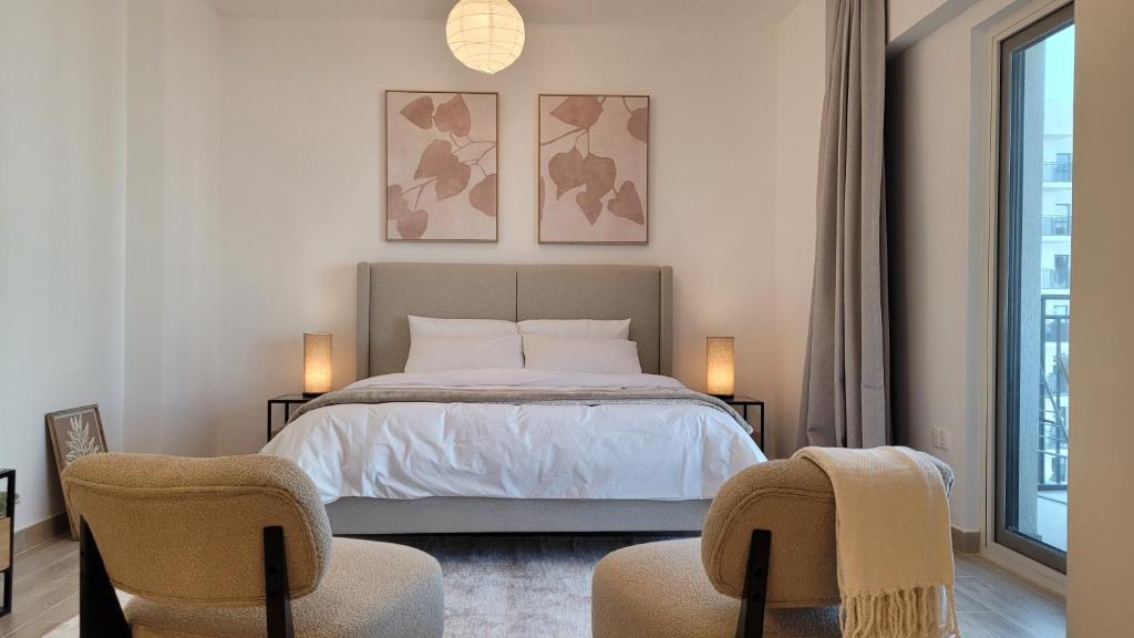 Un dormitorio con una cama con dos sillas y una ventana. en Comfortable & Stylish, Steps from F1 Arena!, en Abu Dabi