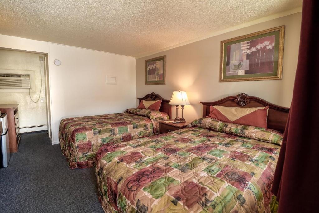 a hotel room with two beds and a lamp at Economy Inn Bloomington in Bloomington