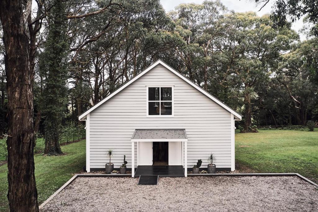 een klein wit huis in een veld met bomen bij The Red Hill Barn in Main Ridge