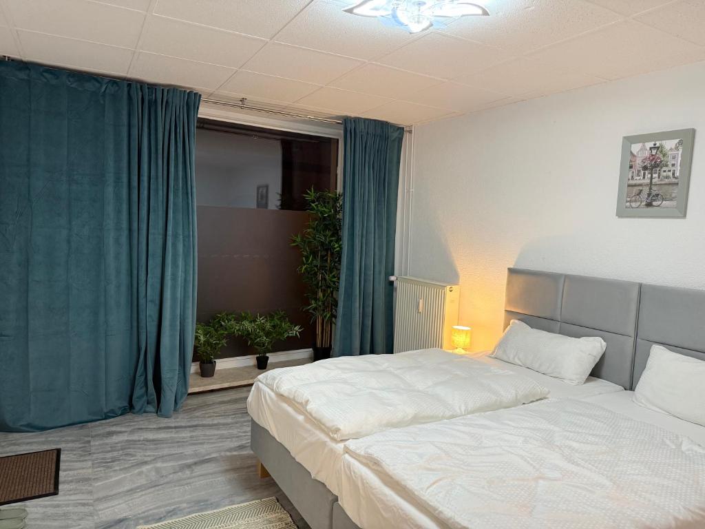 ein Schlafzimmer mit zwei Betten und einem Fenster mit blauen Vorhängen in der Unterkunft Apartment Döbeln Centrum in Döbeln