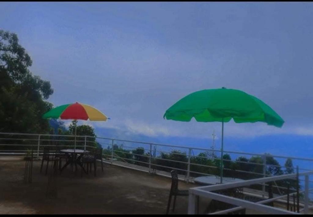 two tables and umbrellas on a balcony with the ocean at Aman magic resort in Takdāh