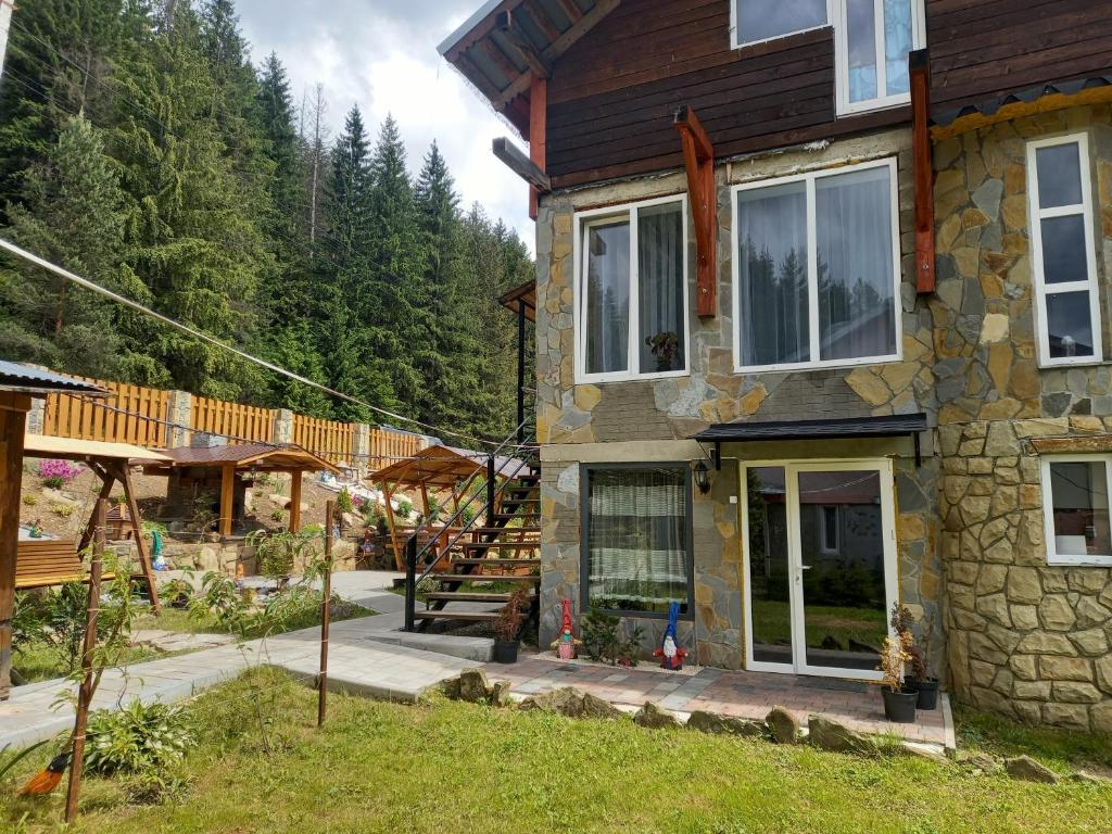 uma casa de pedra com um alpendre e um deque em Шепіт Лісу em Yaremche