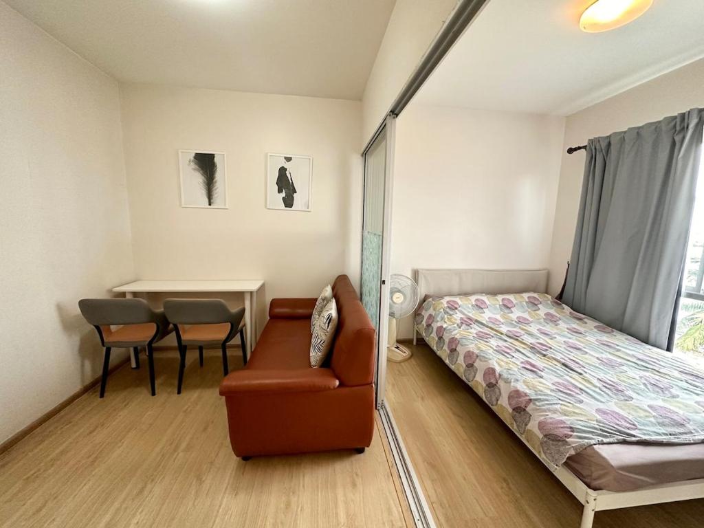 een slaapkamer met een bed, een stoel en een tafel bij Plum condo Bang-yai station in Nonthaburi