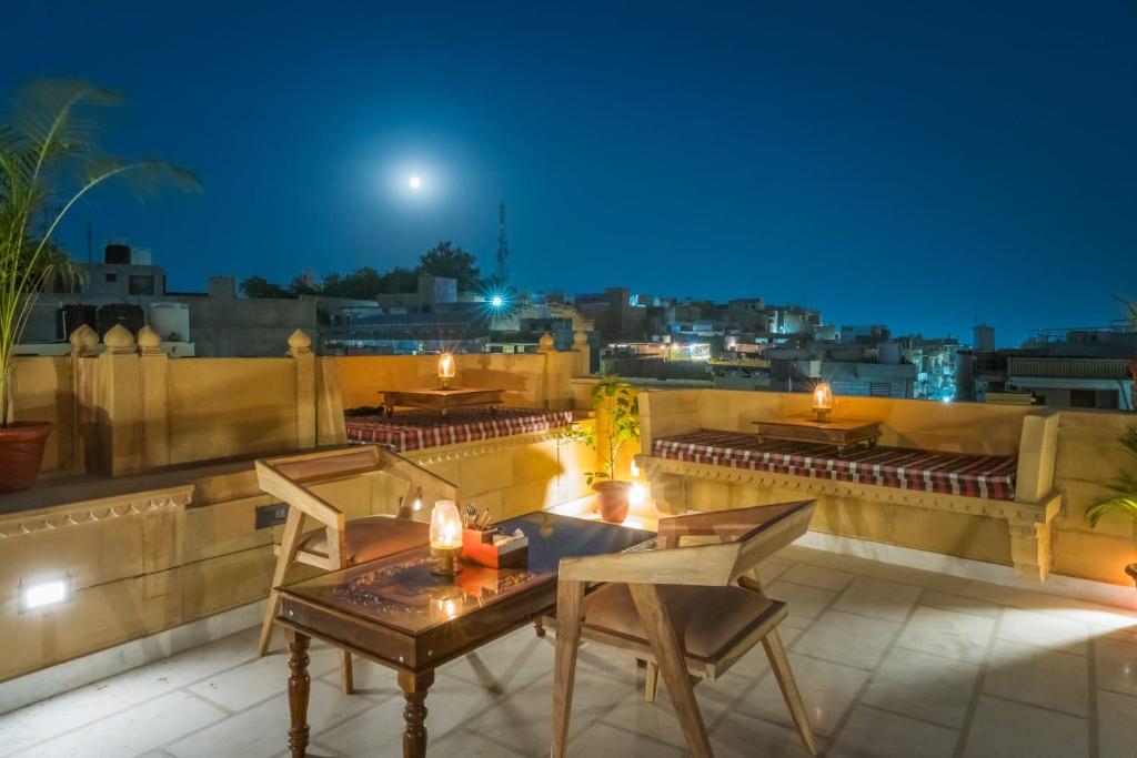 eine Terrasse mit Tischen und Stühlen auf einem Dach in der Nacht in der Unterkunft The second home jaisalmer in Jaisalmer