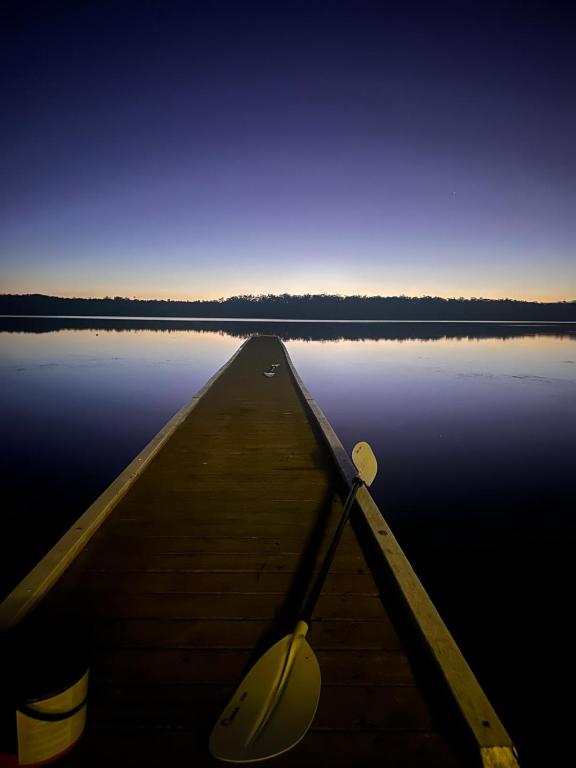 a boat is sitting on a lake with the water at Jerrinja - Absolute waterfront with jetty - 5 mins to Hyams Beach in Erowal Bay