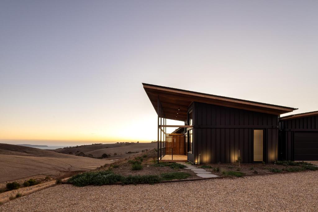 a house on top of a hill with the sun setting at Studio on Forktree – Modern Coastal Retreat in Carrickalinga
