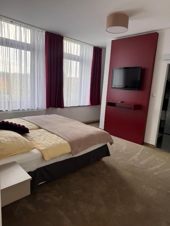 a bedroom with a bed and a flat screen tv at Hotel Restaurant Waldschlößchen in Neheim-Hüsten