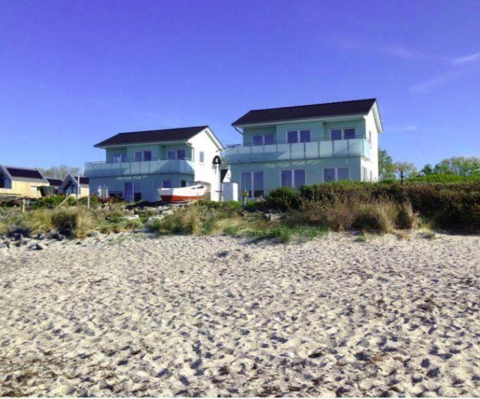 a house on the beach next to a sandy beach at Strandhaus Appartement - Seeschwalbe OG in Fehmarnsund