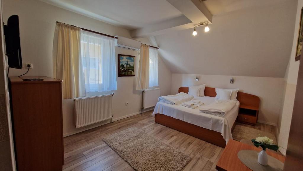 ein Schlafzimmer mit einem Bett und einem Fernseher in der Unterkunft Pensiunea Veronica in Baile Felix