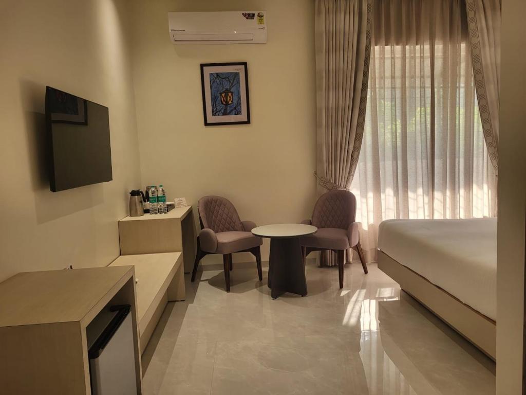 a hotel room with a bed and a table and chairs at Jhansi Hotel in Jhānsi